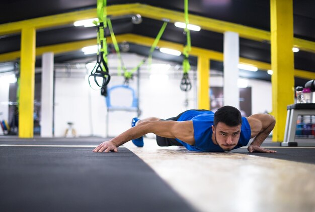 Foto giovane uomo forte facendo flessioni alla palestra di forma fisica trasversale