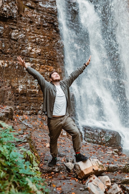 Young strong man hiker looking the waterfall copy space