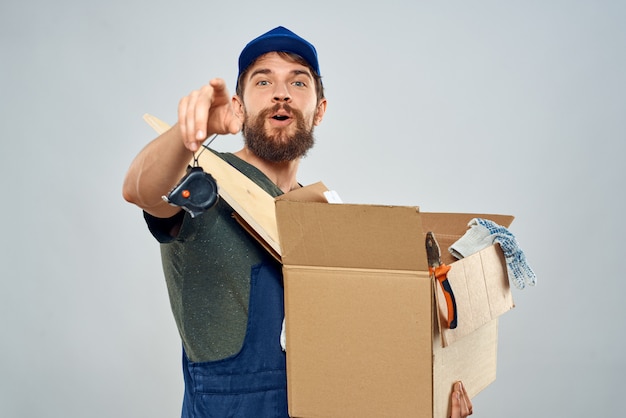 Young strong man in overalls delivers parcels, boxes, goods,\
courier