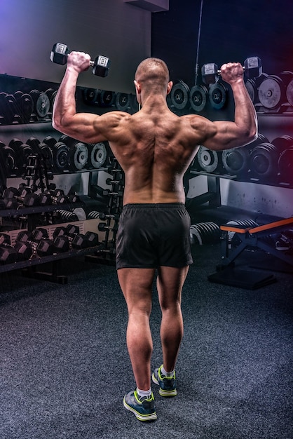 Young strong man training his back in a gym