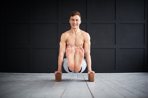 Young strong shirtless man practices yoga at the yoga studio