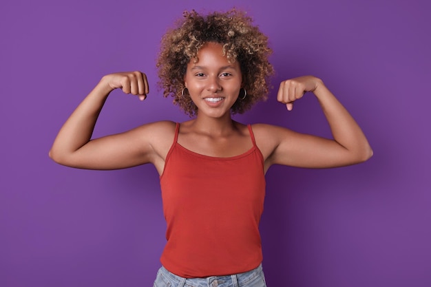 Foto giovane donna afroamericana forte e sorridente che posa in posa di uomo forte in studio