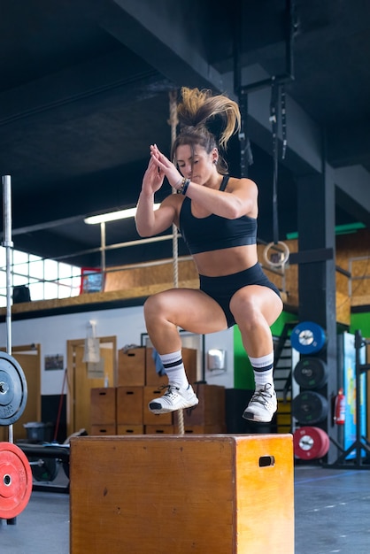 Фото Молодая сильная потная мускулистая девушка с большими мускулами делает хардкорный кроссфит в прыжках на боксе