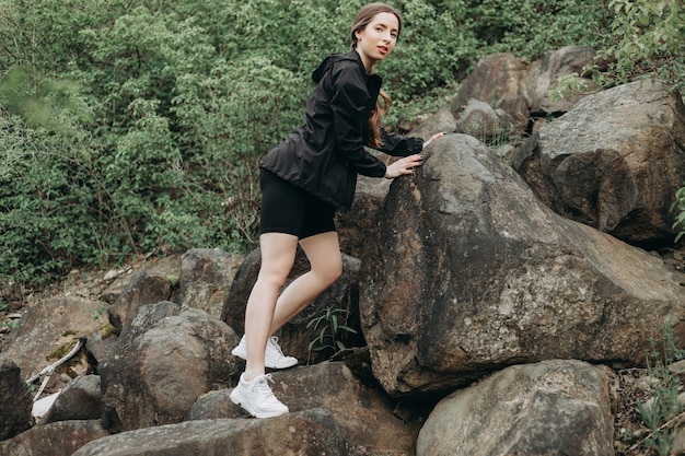 若い強い女性が崖の上に登る障害物を克服し、勇気を持って登る野心的な登山家