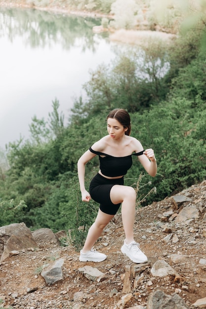 Молодая сильная женщина поднимается на вершину скалы Преодолевая препятствия и мужество Амбициозный альпинист