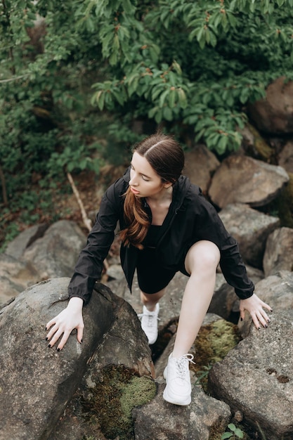 Young strong woman climbs to top of cliff overcoming obstacles\
and courage ambitious climber climb