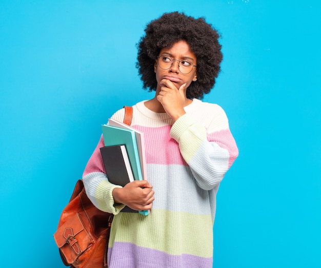 Young student afro woman thinking, feeling doubtful and confused, with different options, wondering which decision to make