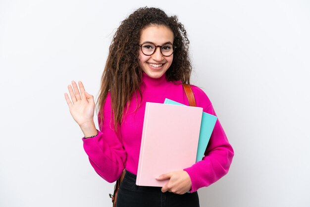 幸せな表情で手で敬礼する白い背景で隔離の若い学生アラブ女性