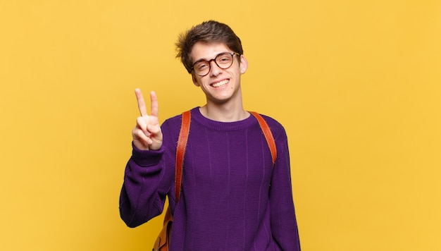 Young student boy against orange wall with a school bag