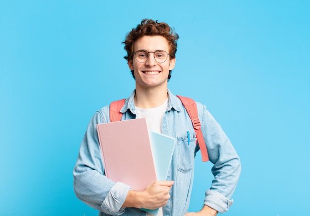 Young student boy smiling happily with a hand on hip and confident, positive, proud and friendly attitude