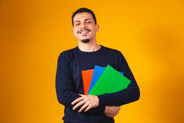 Young student boy on yellow background. happy student boy holding notebook