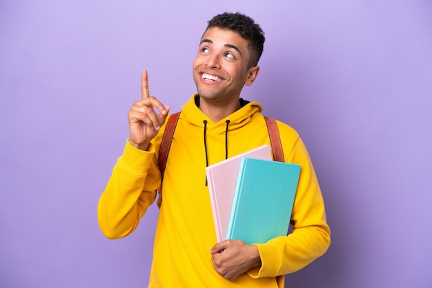 Young student Brazilian man isolated on purple background pointing up a great idea