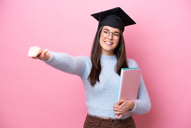 Young student Brazilian woman wearing graduated hat isolated on pink background giving a thumbs up gesture