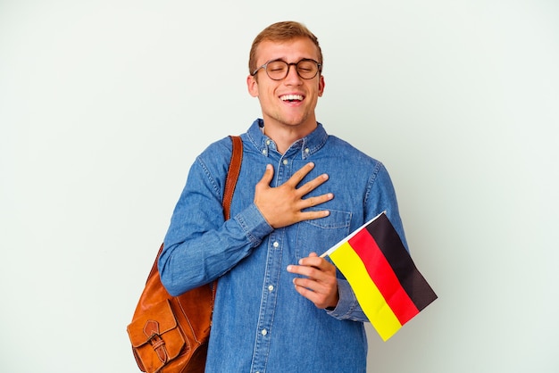 白い背景にドイツ語を勉強している若い学生の白人男性は、胸に手を当てながら大声で笑います。