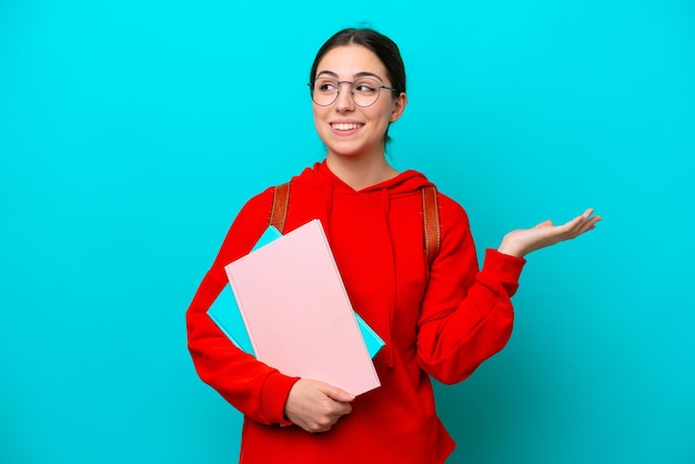 手を上げながら疑問を持つ青の背景に分離された若い学生白人女性