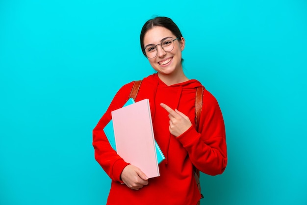 Young student caucasian woman isolated on blue background pointing to the side to present a product