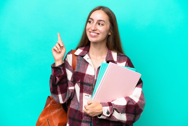 素晴らしいアイデアを指している青い背景に分離された若い学生白人女性