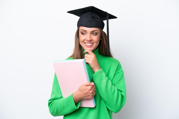 Donna caucasica del giovane studente isolata su fondo bianco che guarda al lato e che sorride