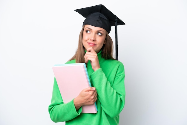 Young student caucasian woman isolated on white background and looking up