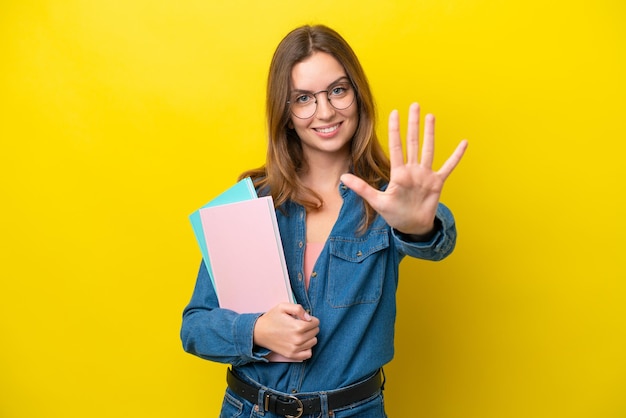 Young student caucasian woman isolated on yellow background counting five with fingers