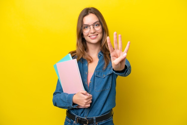 Young student caucasian woman isolated on yellow background happy and counting four with fingers