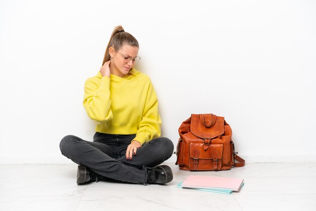 Young student caucasian woman sitting one the floor isolated on white background with neckache