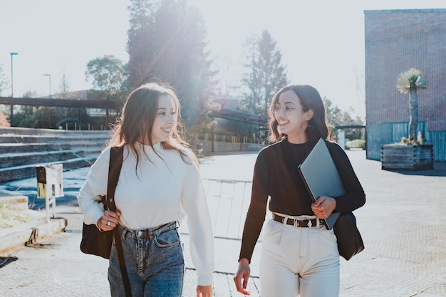 Young student couple going to college class outdoors the campus\
while talking and having a laugh after meeting again after her\
holidays. study together and learning concept. trendy young\
style