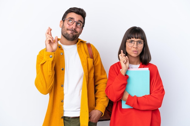 Young student couple isolated on white background with fingers crossing and wishing the best