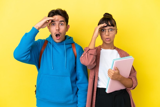 Young student couple isolated on yellow background has just realized something and has intending the solution