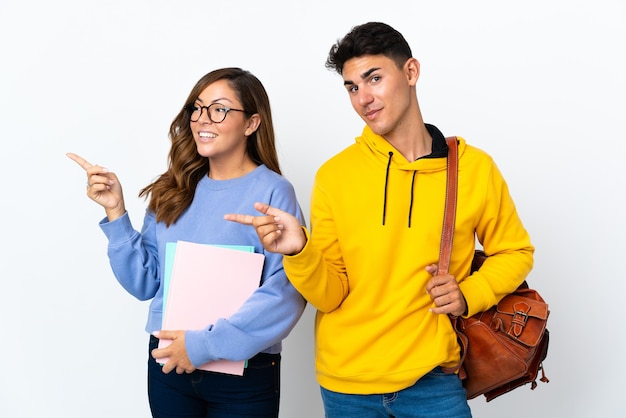 Young student couple on white pointing finger to the side in lateral position