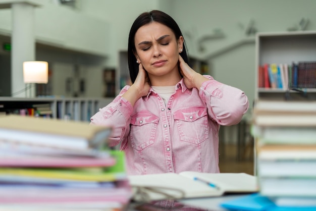 Young student girl reading book and preparing to hard exam\
woman feeling tired while sitting at the library high school\
university campus and knowledge center concept