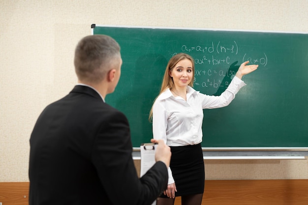 Young student girl takes an exam near the blackboard