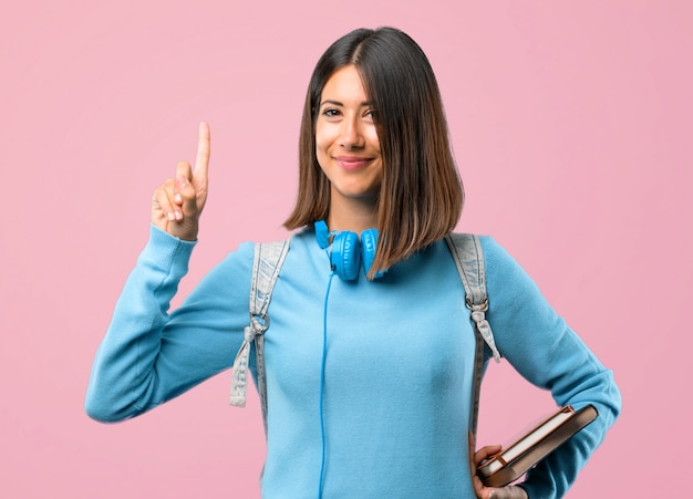 Young student girl with blue sweater and headphones showing and lifting a finger