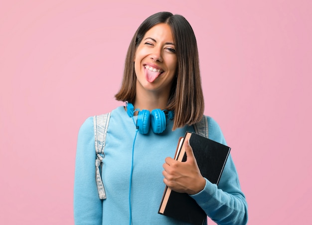 青いセーターと舌を示すヘッドフォンを持つ若い学生の女の子。学校に戻る