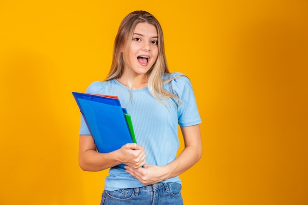 Young student girl with books on yellow background. Back to school.