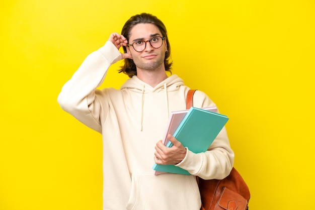 Young student handsome man isolated on yellow background having\
doubts