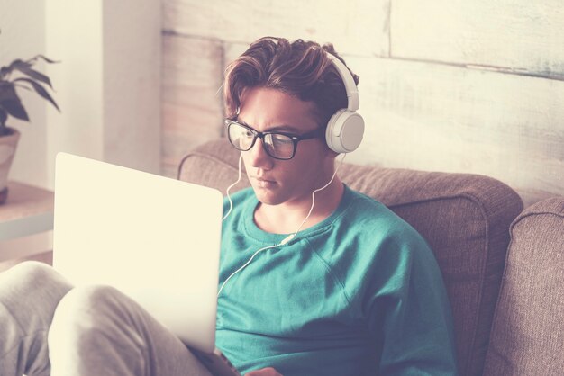 Young student at home with modern laptop computer and headphone studying with internet cnnection 