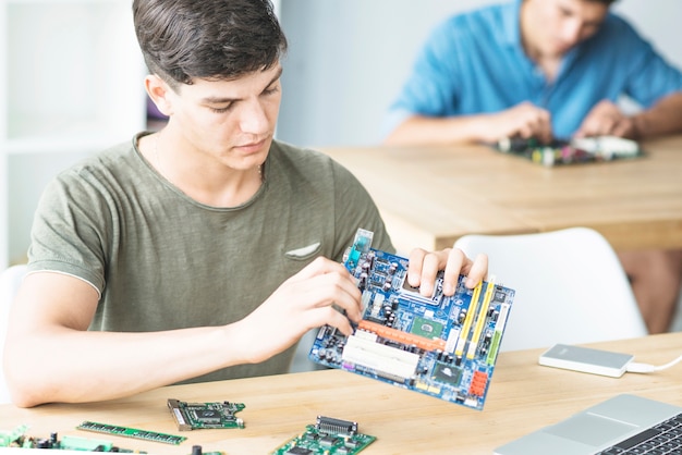 Photo young student learning to assemble motherboard