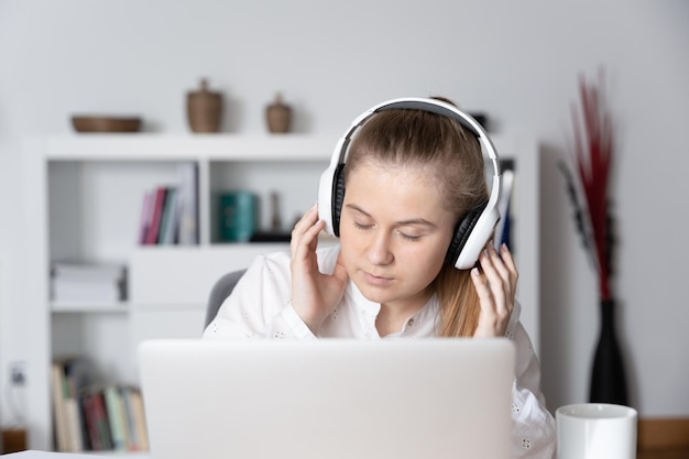 Young student listening to music and relaxing in front of laptop