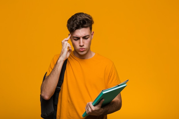 Young student man holding books being shocked, she has remembered important meeting.