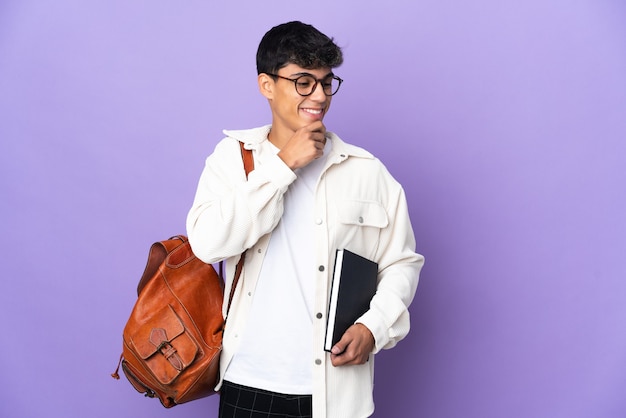 Young student man over isolated purple background looking to the side and smiling