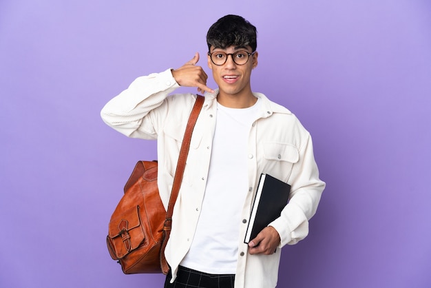 Young student man over isolated purple background making phone gesture. Call me back sign