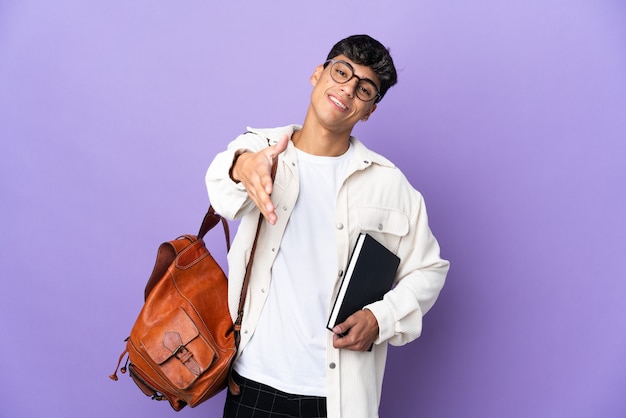 Uomo giovane studente su viola isolato stringe la mano per la chiusura di un buon affare