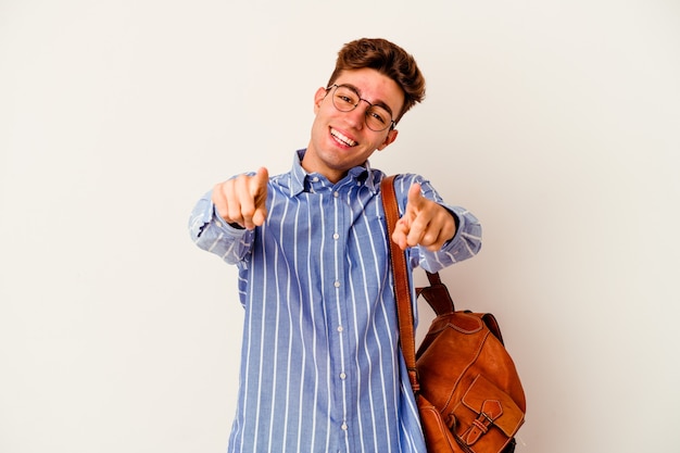 Young student man isolated on white wall cheerful smiles pointing to front.