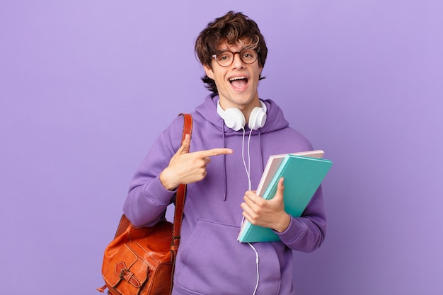 Young student man looking excited and surprised pointing to the side