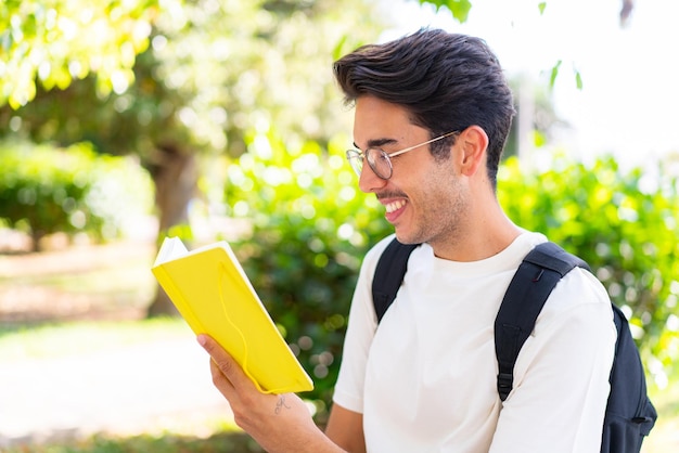 ノートを持って屋外で若い学生の男