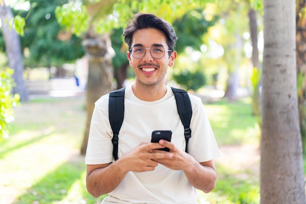 携帯電話を使用して屋外で若い学生の男