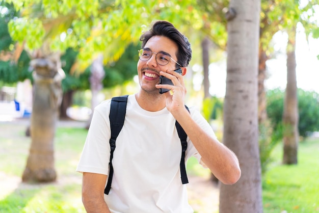 Young student man at outdoors using mobile phone