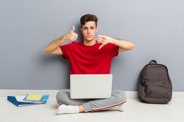 Young student man sitting on his house floor holding a laptop