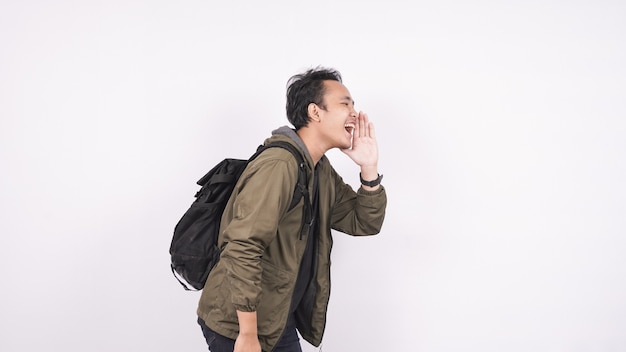 Young student man wearing a bag shouting and yelling isolated on white backgroud